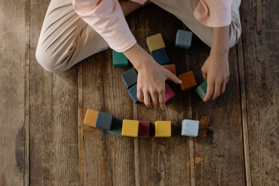 Criança pequena empilhando blocos de madeira coloridos