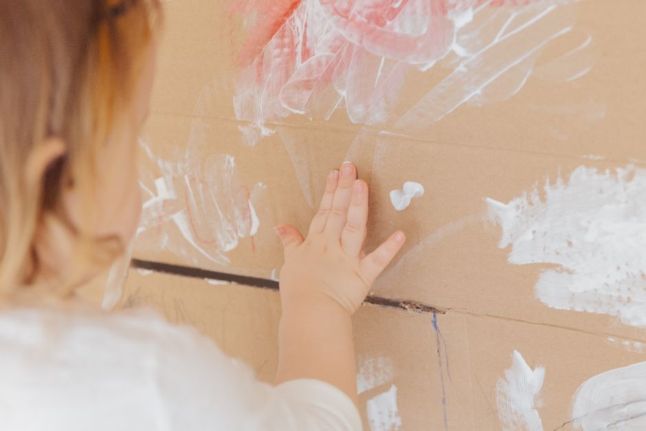 Criança fazendo pintura sensorial comestível com iogurte colorido