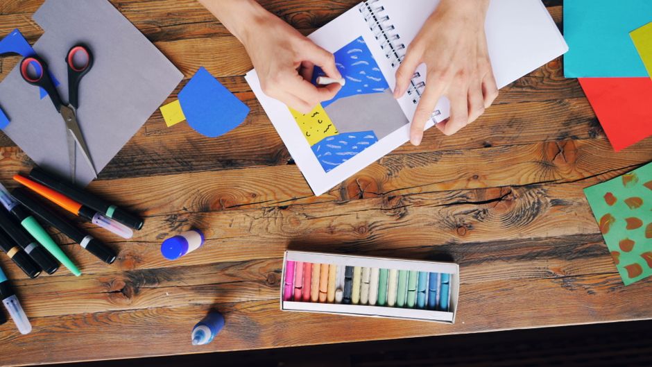 Papel colorido, tesoura e cola sobre a mesa para atividade de recorte