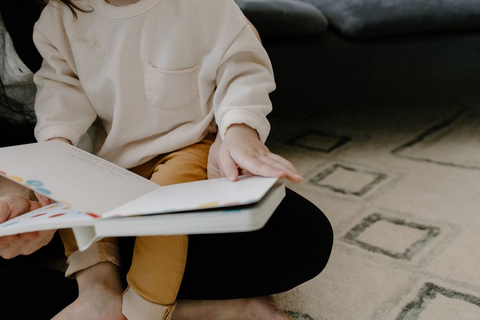 Adulto e criança lendo um livro ilustrado juntos no sofá