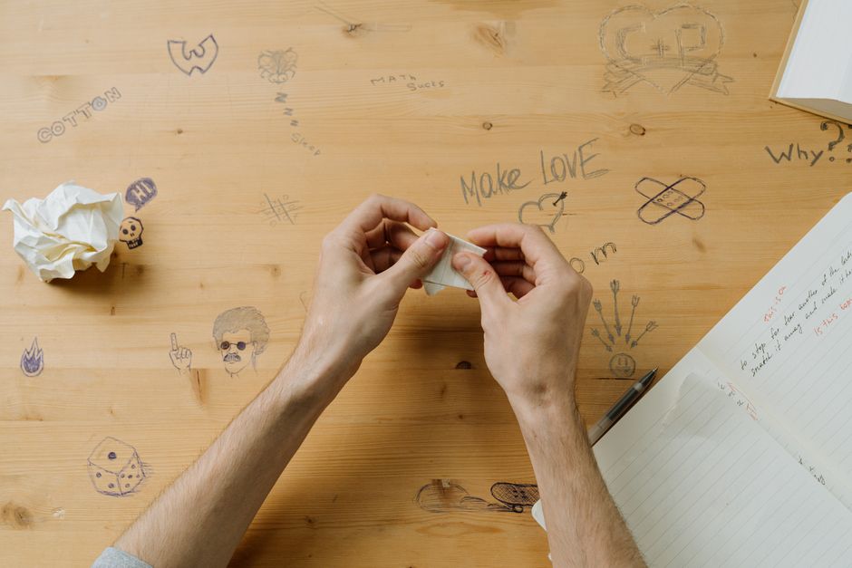Pistas de papel dobradas e escritas à mão sobre a mesa, ao lado de uma caneta