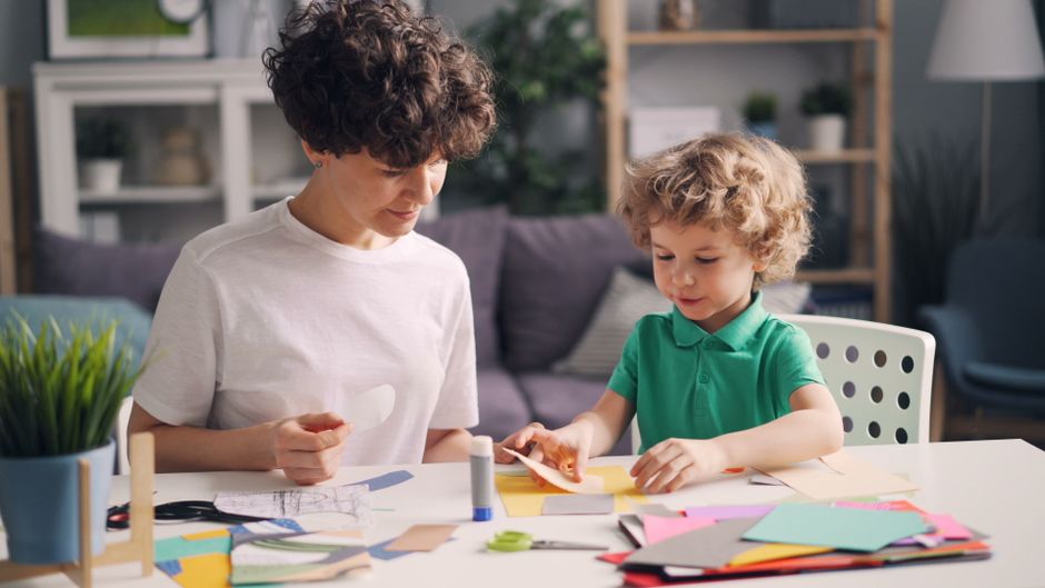 Criança brincando com uma dobradura de papel na mesa