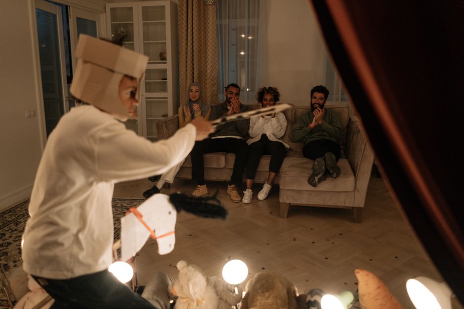Família reunida no escuro assistindo a uma apresentação de teatro de sombras em casa