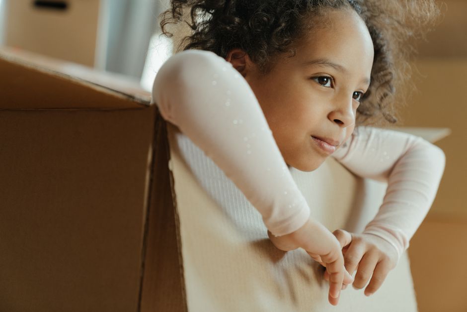 Criança jogando bolinha de meia dentro de um alvo feito de caixa de papelão