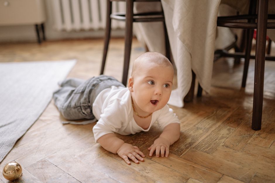 Bebê engatinhando pelo chão de madeira de casa