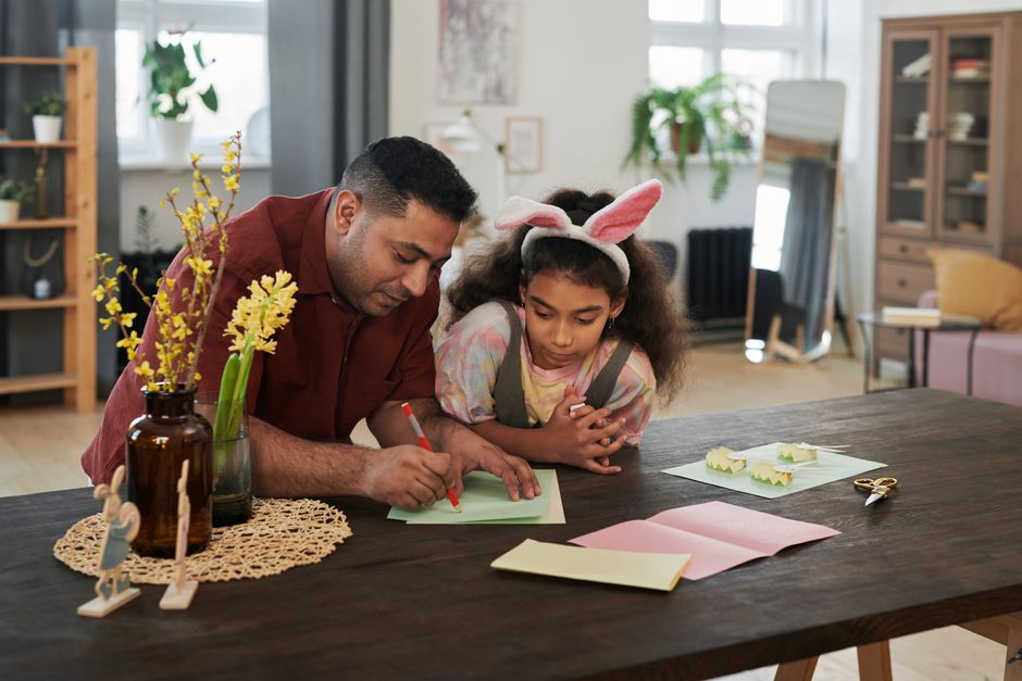 Avô e criança montando um foguete de papel juntos na mesa