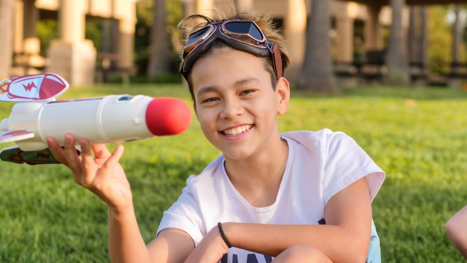 Criança sorrindo orgulhosa segurando o foguete de papel pronto